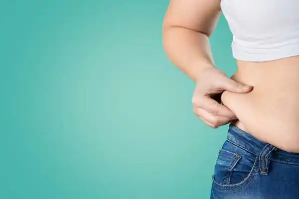Image of woman pinching her love handles to show weight gain Haslemere